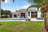 Rear exterior featuring a tile roof, stucco finish, in-ground swimming pool, concrete patio, and floor-to-ceiling glass panel doors
