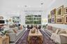 Open-concept interior featuring high ceilings, recessed lighting, neutral tile flooring, and oversized glass sliding doors