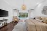 Tray ceiling, wood-finish flooring, and glass sliding doors providing exterior exposure to a swimming pool