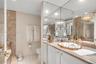 Vanity featuring a custom-shaped basin with gold-tone trim, integrated stone countertop, floor-to-ceiling mirror, and wall-mounted crystal chandelier-