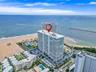 High-rise residential building situated directly on the coastline, featuring prominent ocean frontage, perimeter parking, and on-site swimming pools