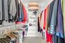 Walk-in closet featuring multi-tiered white wire shelving and built-in hanging rods