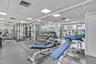 Fitness area featuring a rubberized flooring surface, drop ceiling with recessed panel lighting, and wall-to-wall mirrors