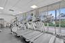 Fitness center featuring rubber flooring, drop ceiling with recessed lighting, and a wall of floor-to-ceiling windows