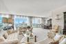 Floor-to-ceiling windows, mirrored wall accents, wall-mounted decorative sconces, and neutral carpeting