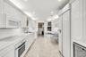 Kitchen featuring high-gloss white cabinetry, stone flooring, built-in panel-ready refrigerator, stainless steel oven, and integrated wine storage