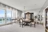 Floor-to-ceiling windows, full-wall mirrored accent, expansive balcony, and an overhead crystal chandelier