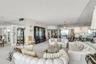 Expansive living space featuring wall-to-wall mirrored surfaces, a built-in floor-to-ceiling cabinet, dual multi-tiered chandeliers, and neutral wall-
