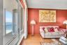 Floor-to-ceiling windows featuring ocean scenery, wood-finish flooring, and an attached balcony with a metal railing
