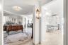 Foyer area featuring recessed tray ceiling, polished tile flooring, mirrored wall accents, and ornamental wall-mounted light fixtures