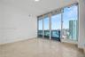 Floor-to-ceiling glass panel windows, polished stone flooring, and a private balcony with metal railings