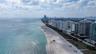 Aerial coastal perspective featuring a direct sandy shoreline and clear ocean waters