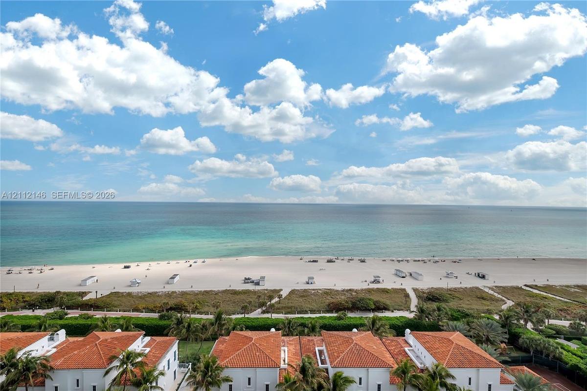 Exterior perspective showcasing terracotta-tiled roofs, sandy shoreline, and expansive ocean scenery