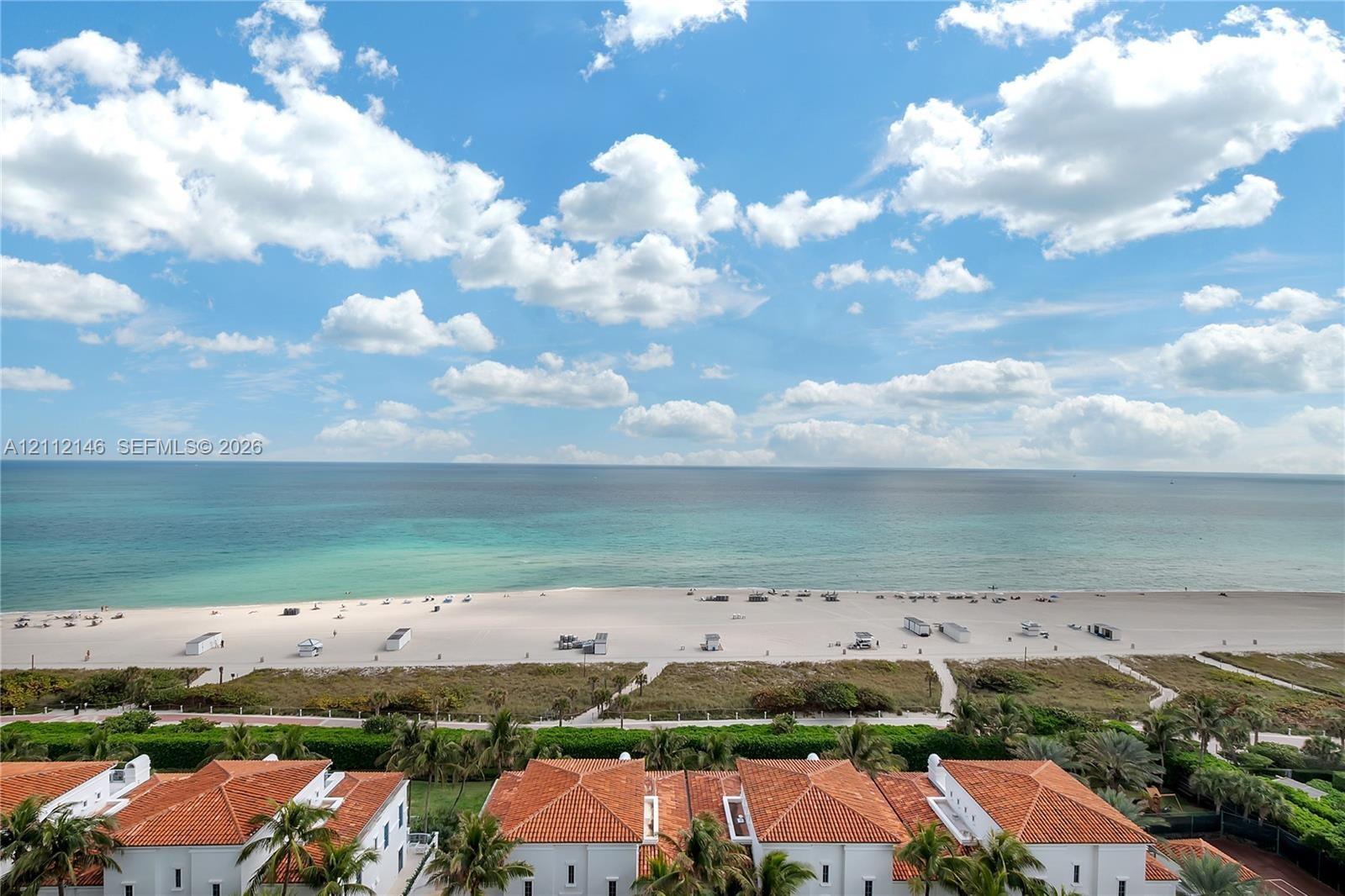 Exterior perspective showcasing terracotta-tiled roofs, sandy shoreline, and expansive ocean scenery