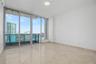 Floor-to-ceiling glass sliding doors, stone tile flooring, and a private balcony