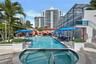Outdoor swimming pool featuring a built-in spa, tile decking, integrated tiered levels, and overhead canopy shading