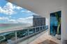 Covered balcony featuring stone tile flooring and glass pane railing with metal accents