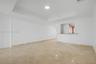Open-concept interior featuring high tray ceilings, polished natural stone flooring, and a pass-through counter with a stone surface