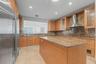 Kitchen featuring natural wood cabinetry, stone countertops, stainless steel appliances, a central island, and recessed lighting