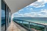Covered balcony featuring tile flooring, full-height sliding glass doors, and a glass-paneled railing overlooking the ocean