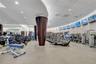 Fitness center featuring a curved wall design, mirrored walls, recessed ceiling lighting, tapered columns with dark wood-finish accents, and multiple 