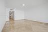 Spacious interior featuring large-format stone flooring laid in a diamond pattern, crisp white wall finishes, crown molding, and recessed ceiling ligh