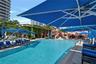 Swimming pool featuring tile edging, stone-paver decking, and structural shade canopies