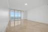 Floor-to-ceiling sliding glass doors, polished stone tile flooring, crown molding, recessed lighting, and a private balcony