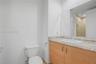 Bathroom featuring a vanity with light-tone wood-finish cabinetry, a neutral-toned stone countertop, an integrated oval sink, and a large-format vanit