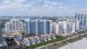 Coastal high-rise complex featuring white sand beach access, terracotta-roofed villas, multiple swimming pools, and tennis courts