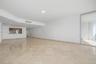 Open-concept interior featuring large-format stone tile flooring, recessed ceiling lighting, crown molding, a service pass-through window, and floor-t