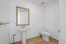 Pedestal sink featuring a metallic faucet, framed wall-mounted mirror, white porcelain toilet, and tile flooring