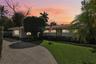 Single-story residence featuring a clay tile roof, stone masonry accents, a paved driveway, and manicured landscaping