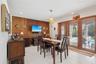 Dining area featuring white tile flooring, wood-paneled accent wall, recessed lighting, spherical pendant light, and sliding glass doors with wood bli