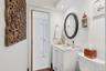 Bathroom featuring a vanity with an integrated basin, a polished chrome faucet, an oval wall-mounted mirror, and louvered closet doors