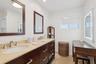 Double vanity with dark wood cabinetry, light-toned stone countertop, dual undermount sinks, and polished chrome fixtures