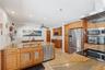 Kitchen featuring wood cabinetry, stone countertops, stainless steel appliances, a dual-basin sink, and recessed lighting