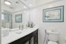 Bathroom vanity featuring a solid surface countertop, integrated sink, dark-toned cabinetry, full-width mirror, and shower enclosure with a glass door