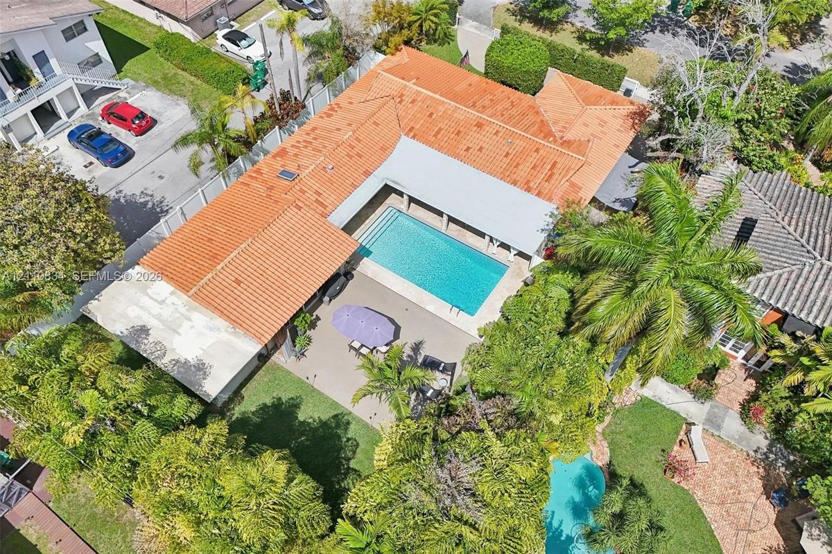 Aerial view featuring a tile roof, an in-ground swimming pool, a covered patio, and landscaped grounds