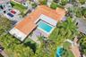 Aerial view featuring a tile roof, an in-ground swimming pool, a covered patio, and landscaped grounds