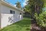 Side exterior featuring stucco siding, white-trimmed horizontal sliding windows, a manicured lawn, and mature perimeter landscaping