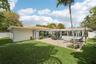 Rear exterior featuring a concrete patio, rectangular swimming pool, clay tile roof, and enclosed yard with perimeter fencing