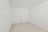 Enclosed space featuring white-painted masonry walls, a painted concrete floor, and a textured ceiling