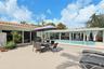 Extensive paved patio featuring an in-ground swimming pool, clay tile roof, and covered outdoor area with stone column supports
