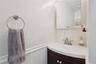 Dark wood-finish vanity with integrated sink, brushed nickel faucet, wall-mounted mirror, and white wainscoting