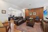 Living area featuring wood-finish flooring, a wood-paneled accent wall, a distinctive arched architectural opening, and recessed lighting