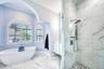 Updated primary bath with walk in shower and separate tub.  Wall mounted vanities