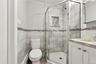 Corner shower featuring a glass enclosure and built-in tiled niche, vanity with stone-finish countertop, and full-height wall tiling with decorative m