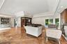 Expansive room featuring intricate parquet wood-finish flooring, a tiered tray ceiling with recessed lighting, custom built-in cabinetry, a wet bar wi