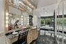 Custom-built vanity with stone countertop and integrated lighting, featuring an ornate architectural mirror frame, polished stone flooring, and a jett